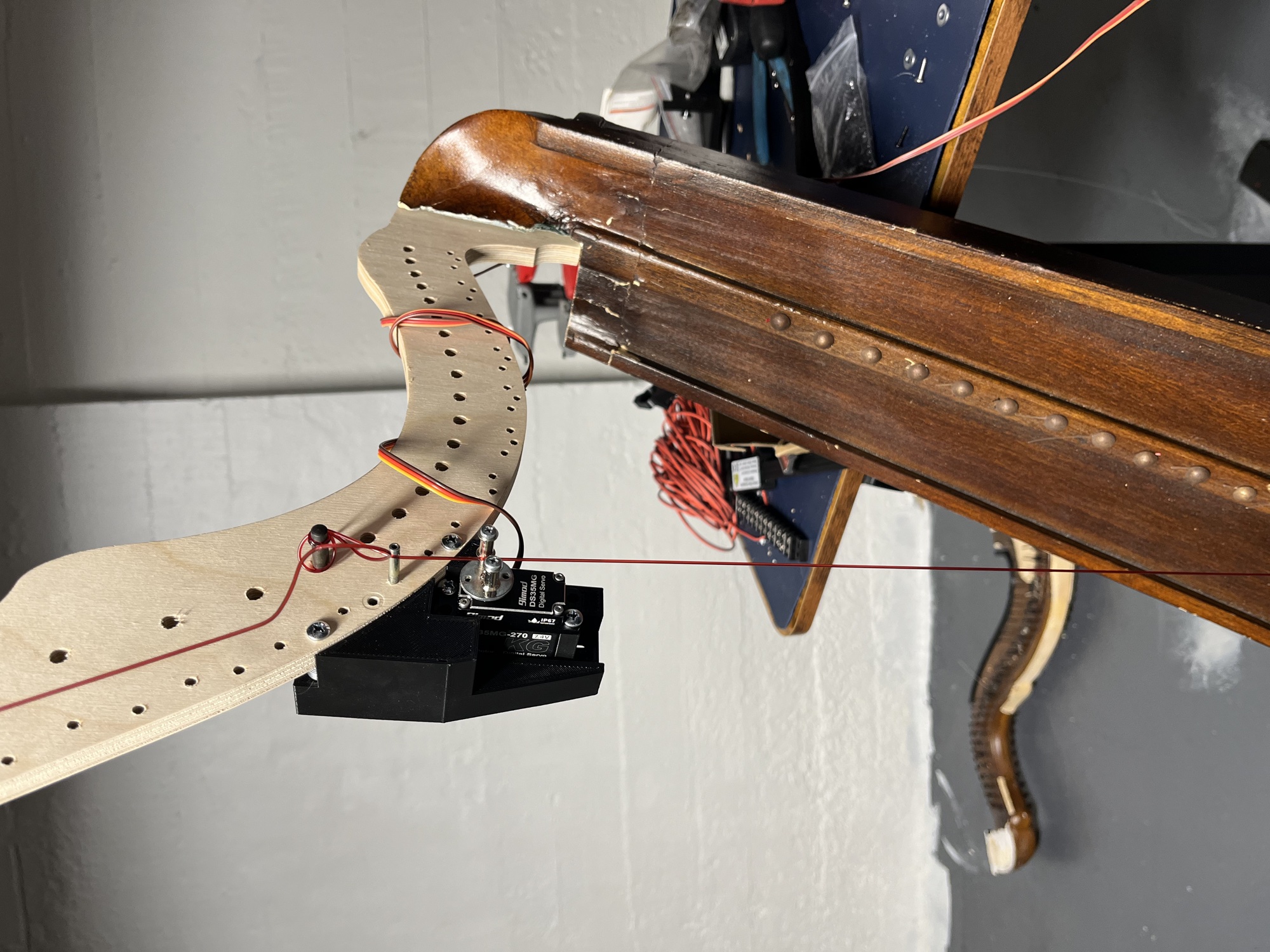 A Smart DS35MG digital servo mounted to the CNC-cut neck in the workshop, driving a single red string; the discarded original neck lies on the floor behind.