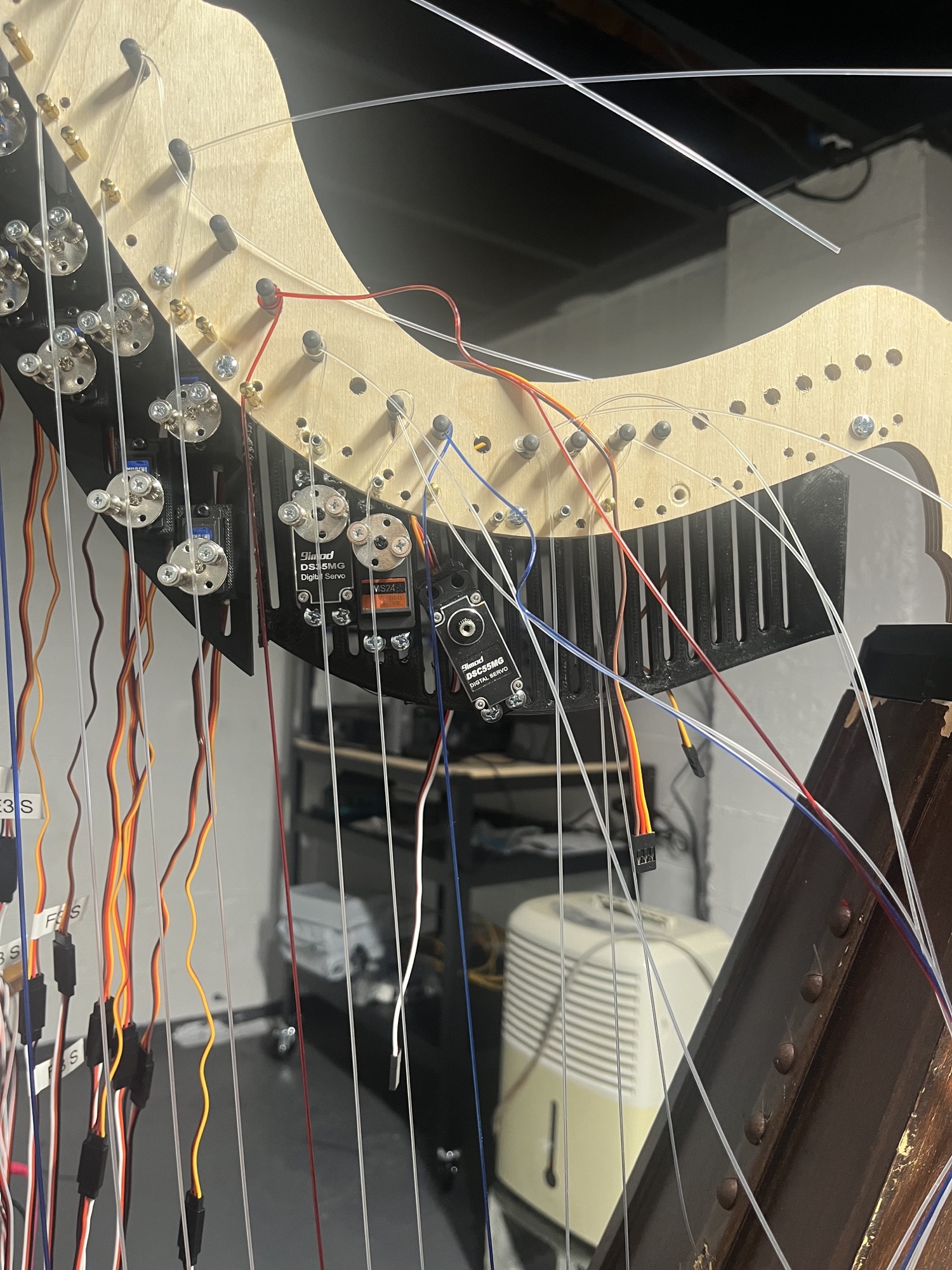 The CNC-cut neck mid-changeover: rows of small blue-label micro servos mounted two per string on a black 3D-printed bracket, with the original larger 9imod DS35MG and DSC55MG servos still hanging beside them.